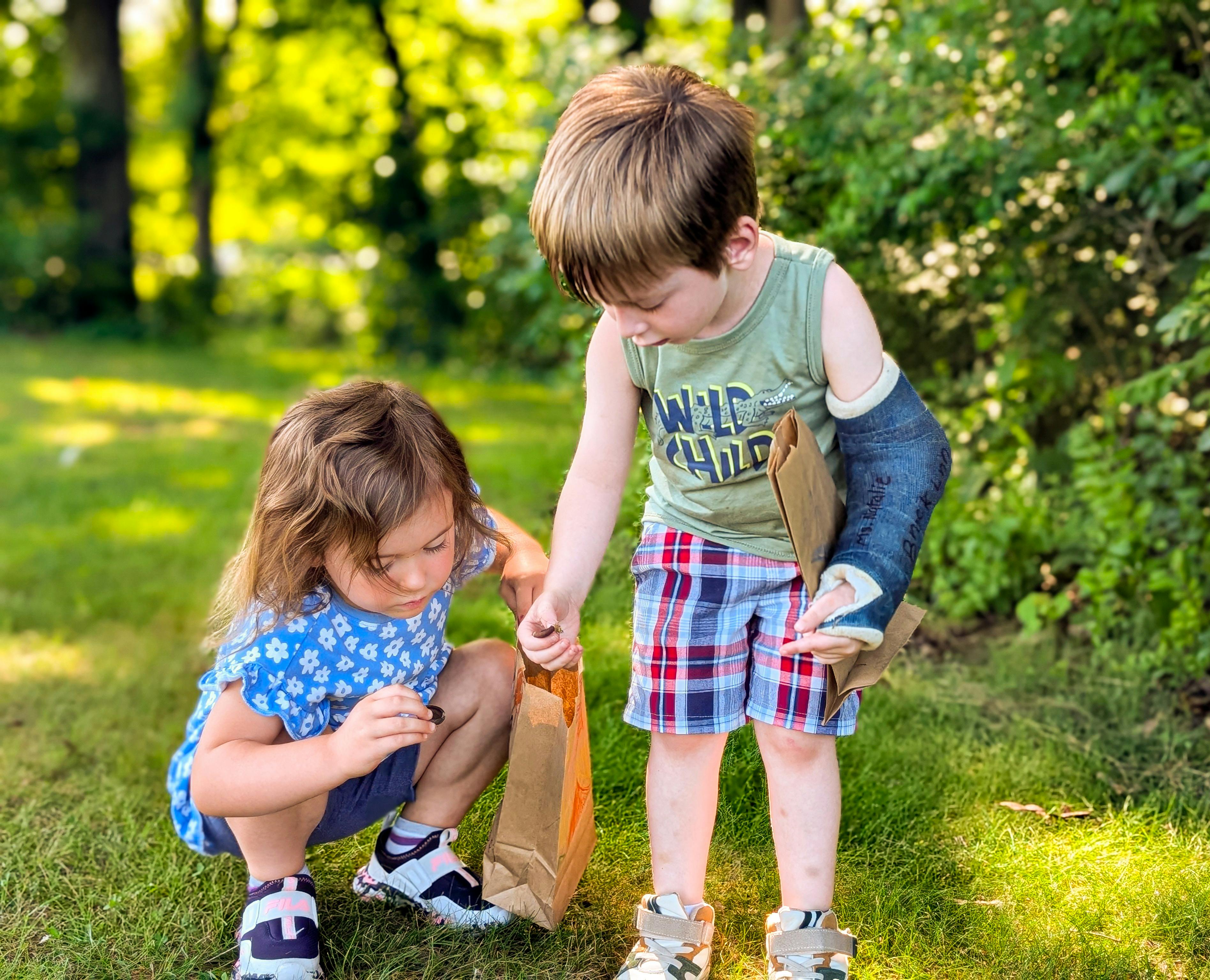 Two children looking into a paper bag outdoors