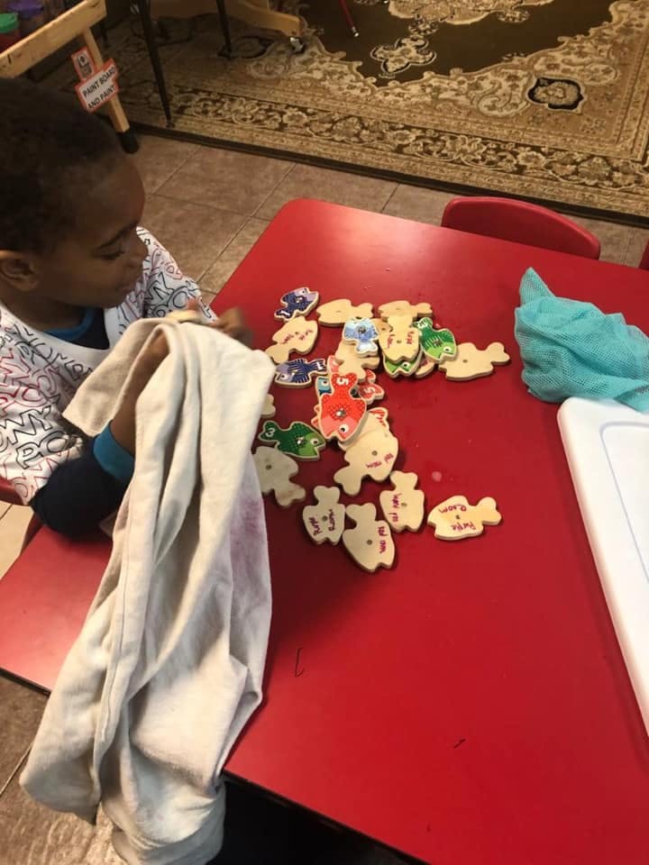 Child at a red table with fish-shaped puzzle pieces