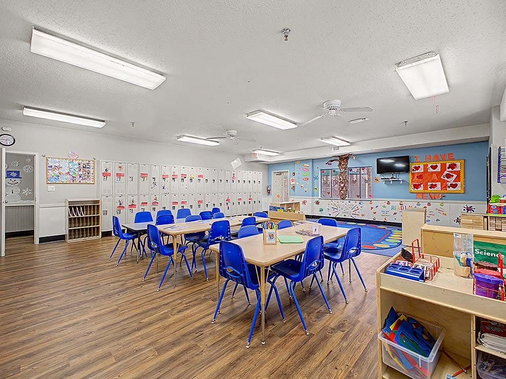 Classroom with blue chairs and light-colored tables, lockers along the wall