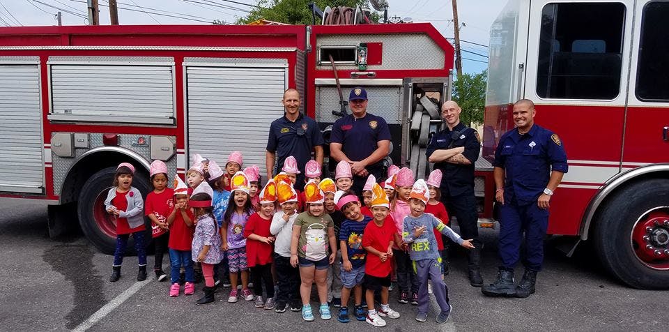 Group of children and adults in front of fire trucks
