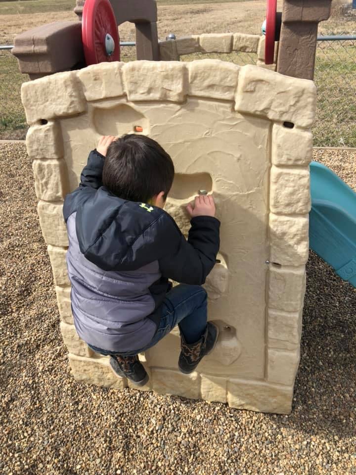 Child climbing a rock wall on a playground
