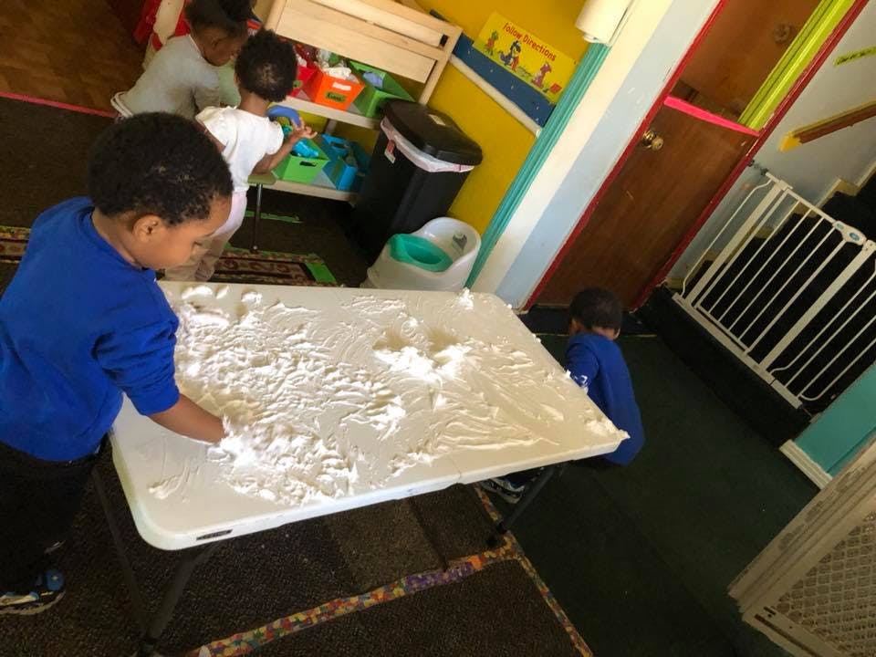 Child playing with white powder on a table