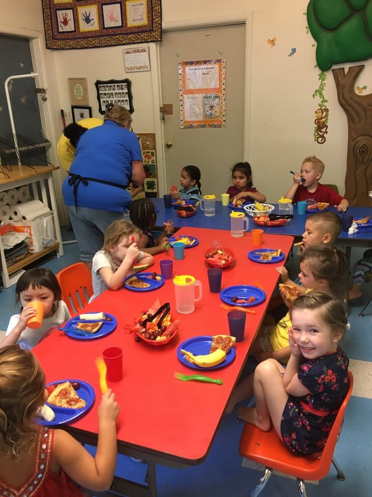 Children eating at a red table in a classroom