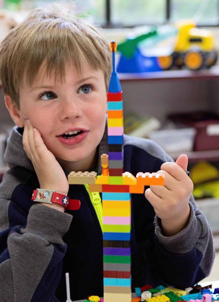 Child looking at a tall, colorful structure made of building blocks