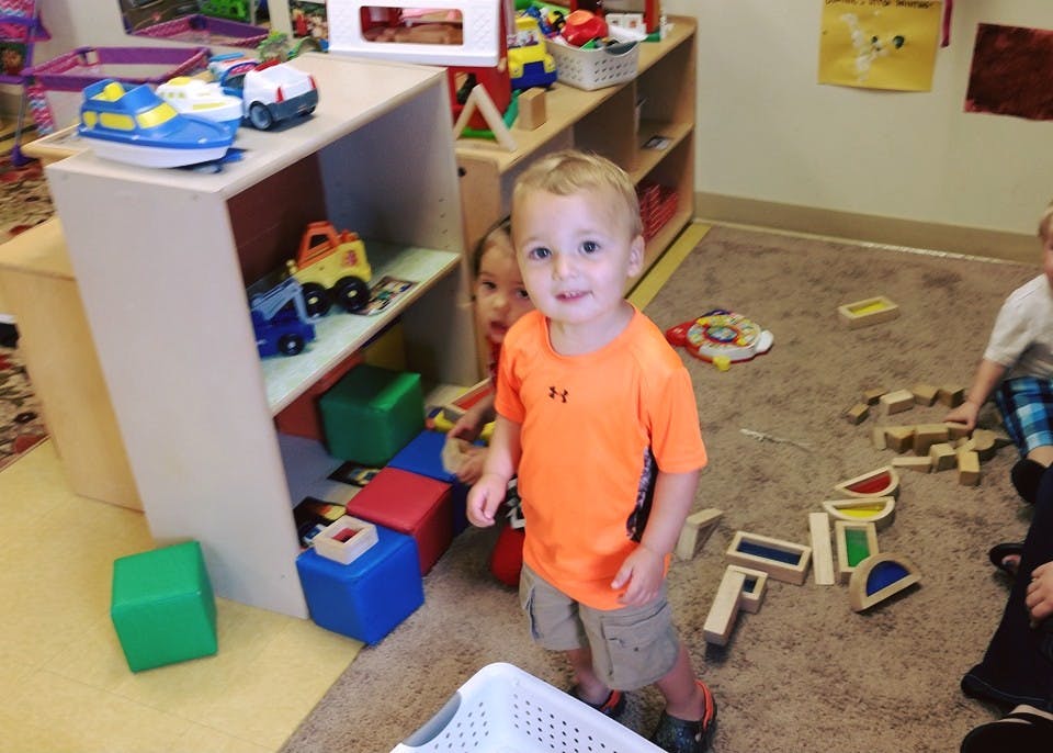 Child standing in a room with toys and blocks