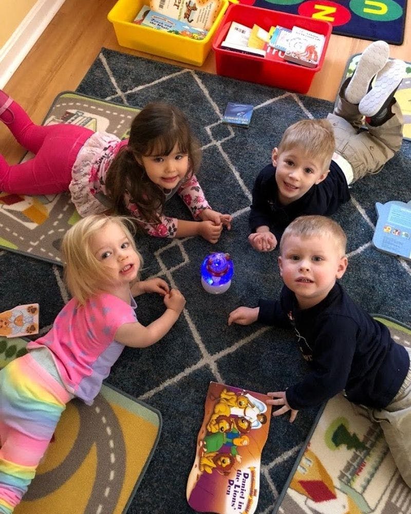Four children lying on a rug looking at a glowing toy