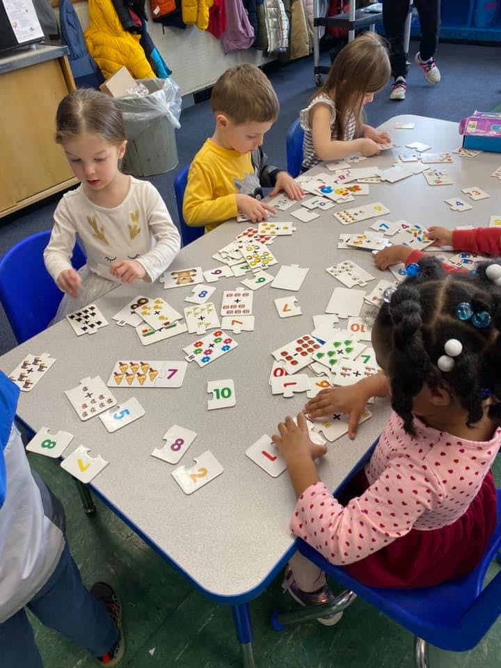 Children at a table playing with number cards