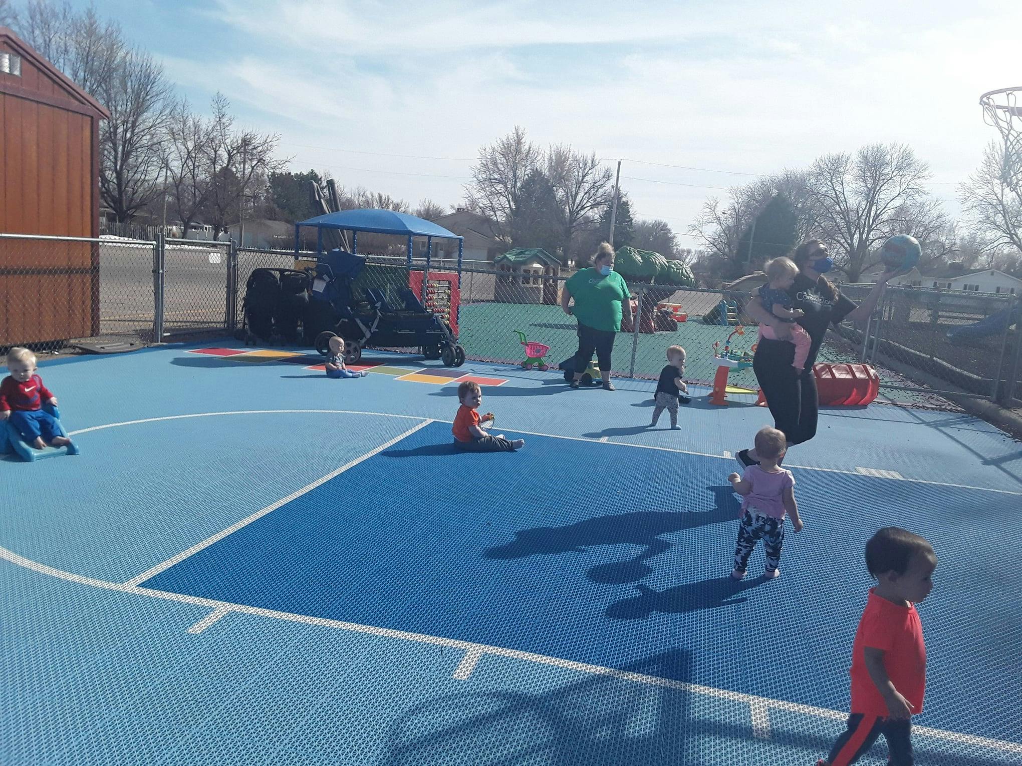 Adults and children on a blue outdoor court