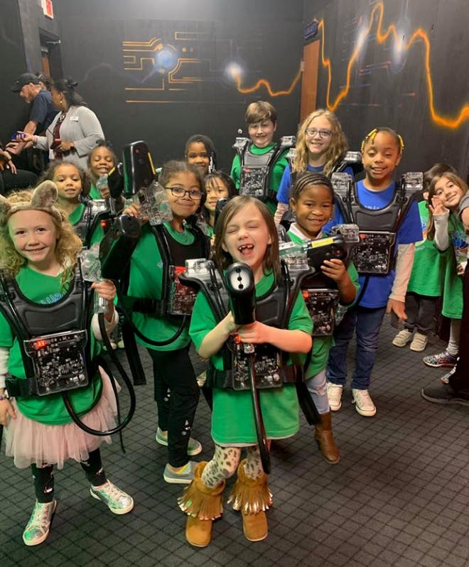 Group of children wearing laser tag vests and holding laser tag guns