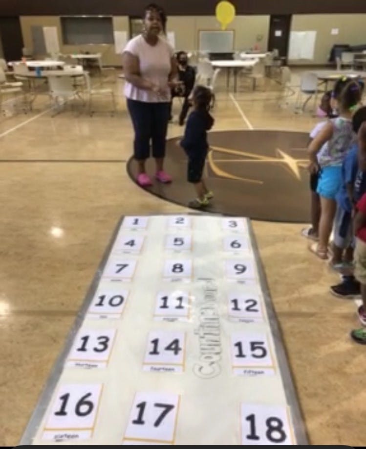 Person and children standing near a number mat on a mat