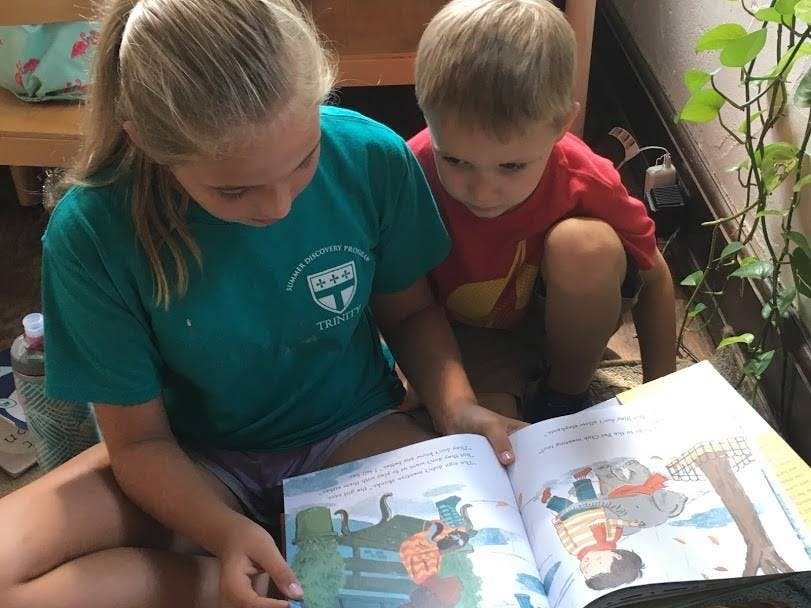 Teen and child reading a book together