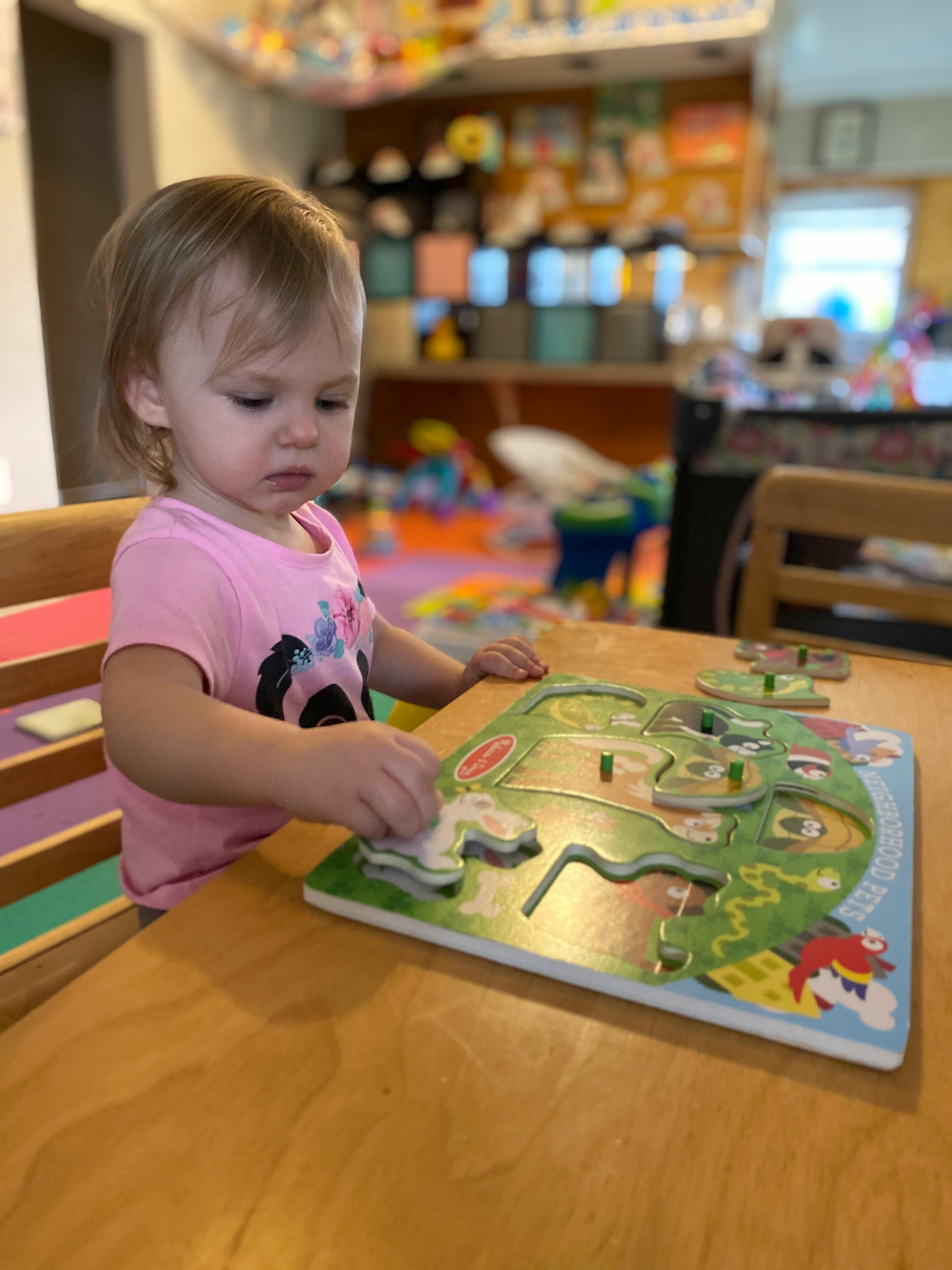 Child playing with a wooden puzzle on a table