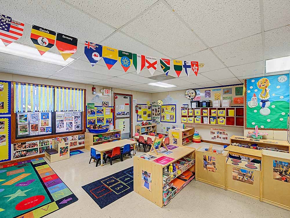 Colorful empty classroom with small tables, chairs, and learning materials