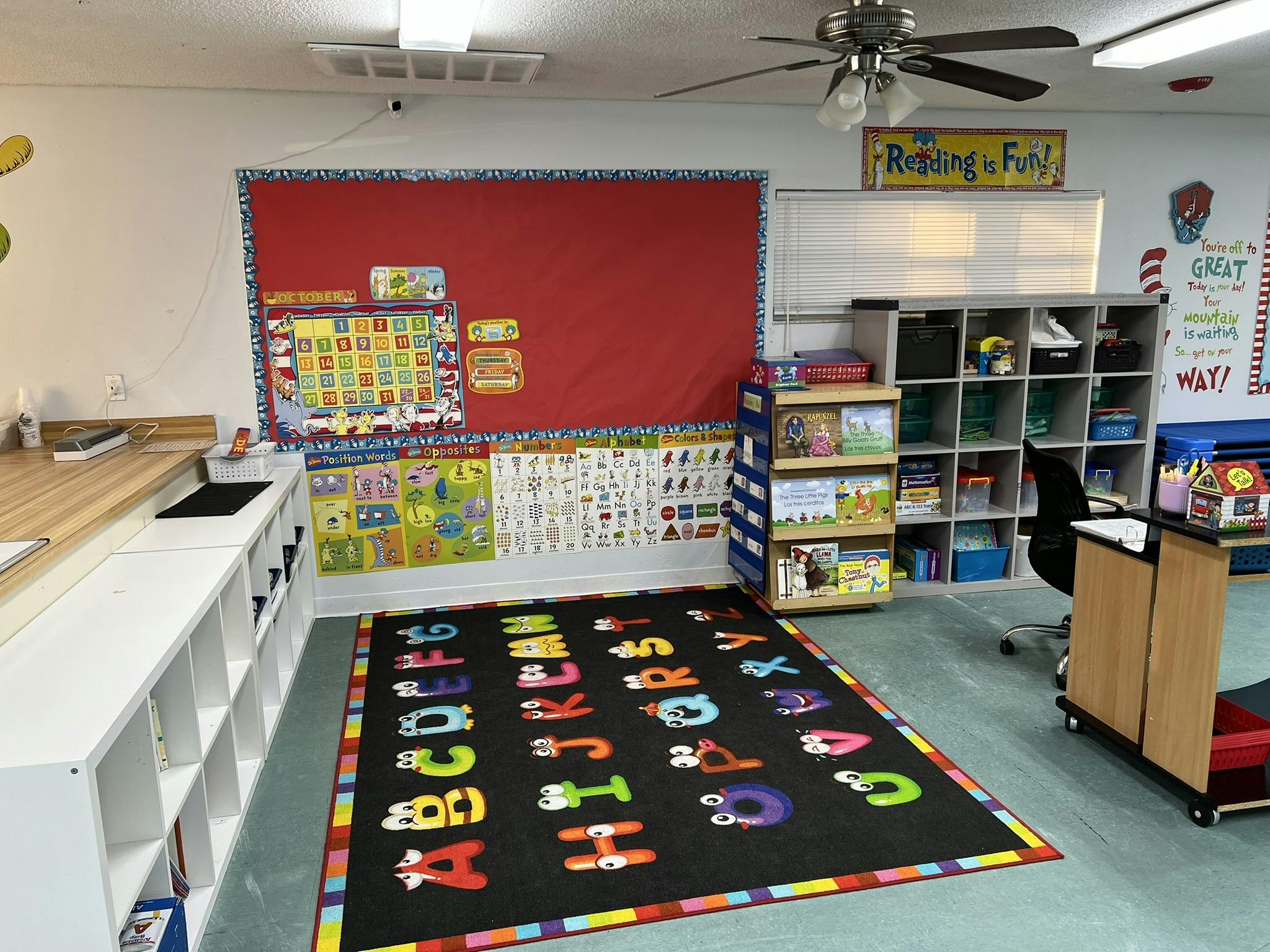 Classroom with an alphabet rug, bulletin board, and storage shelves