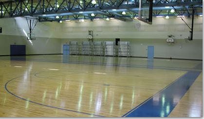 Empty indoor basketball court with wooden floor and blue markings