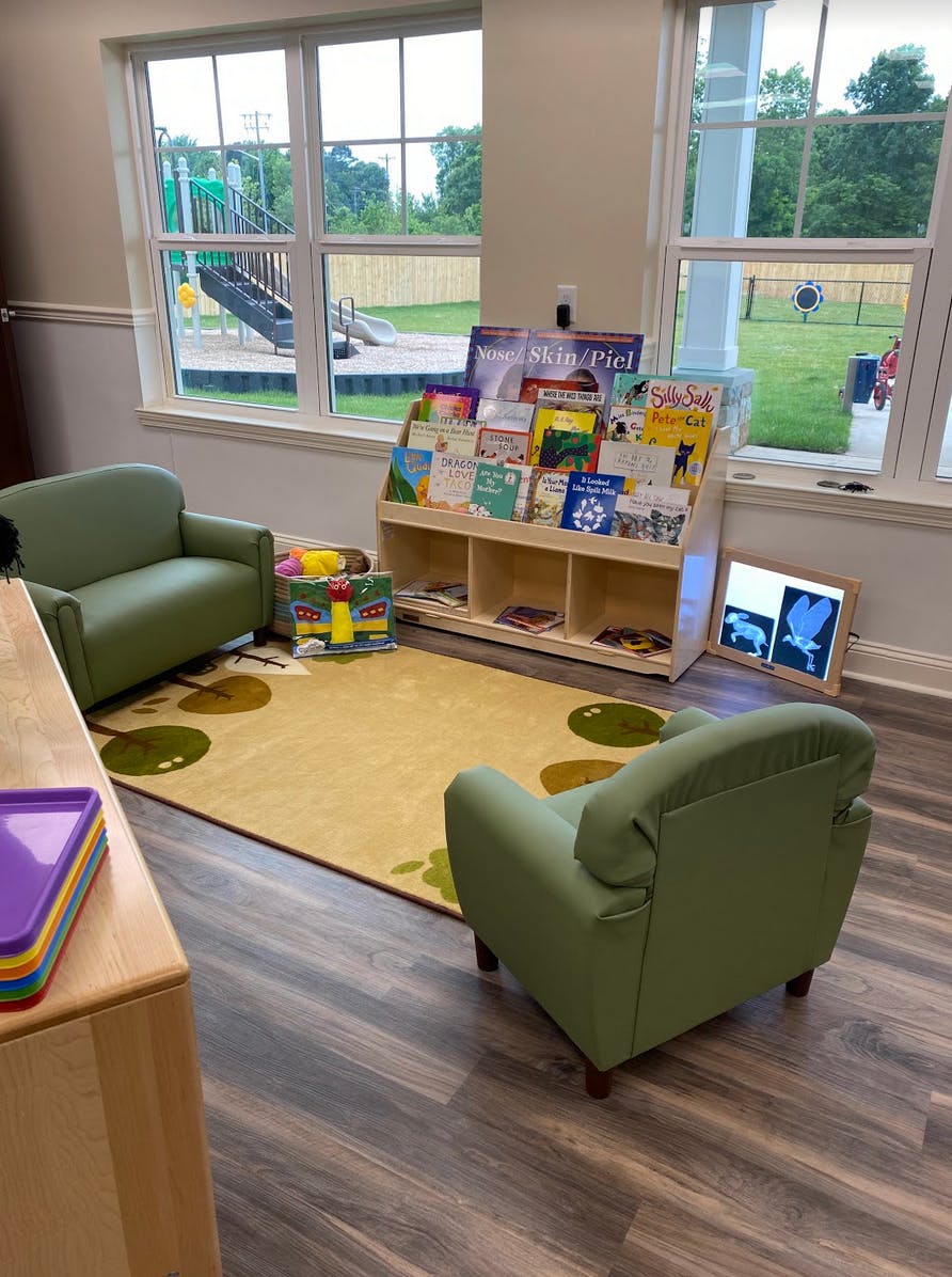 Children's reading area with small chairs, a bookshelf, and a rug