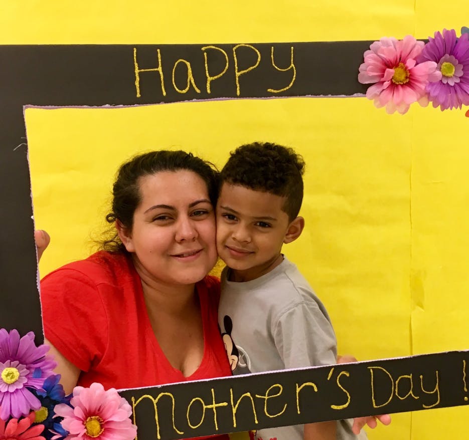 Person and child posing in a photo booth frame with "Happy Mother's Day" text
