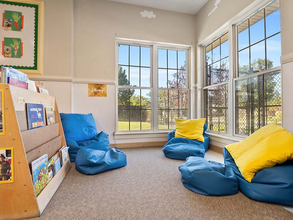 Library reading nook with blue beanbag chairs, yellow pillows, and bookshelves