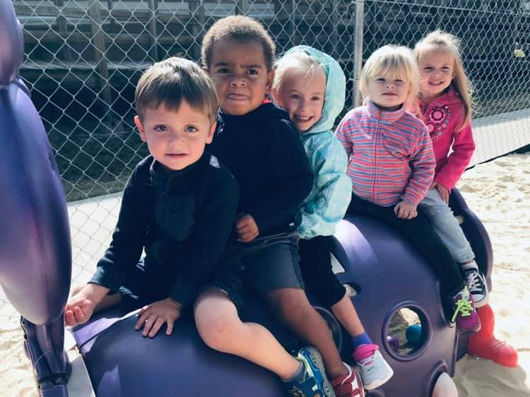 Group of children sitting on a purple playground structure