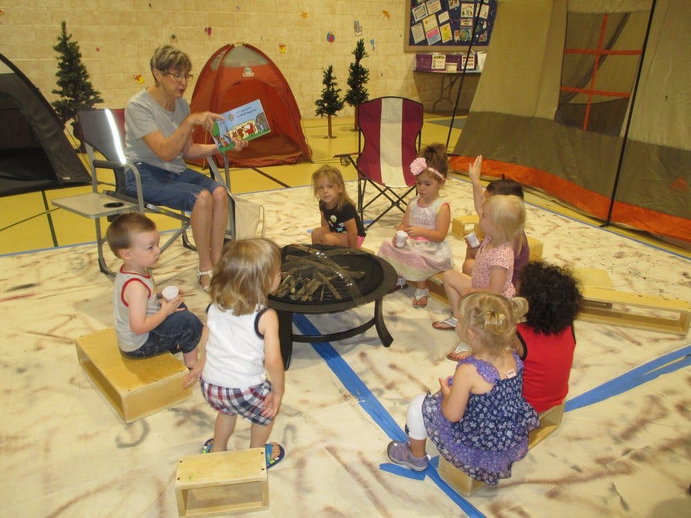 Person reading a book to a group of children in a classroom