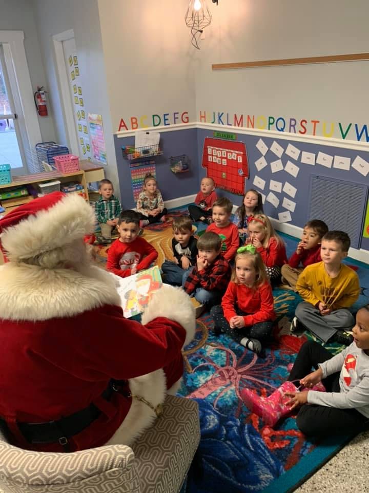Person in Santa costume reading to a group of children in a classroom