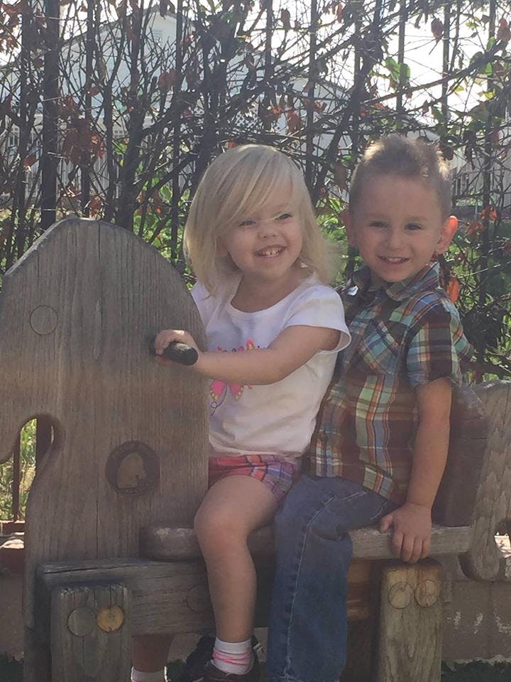 Two children sitting on a wooden bench