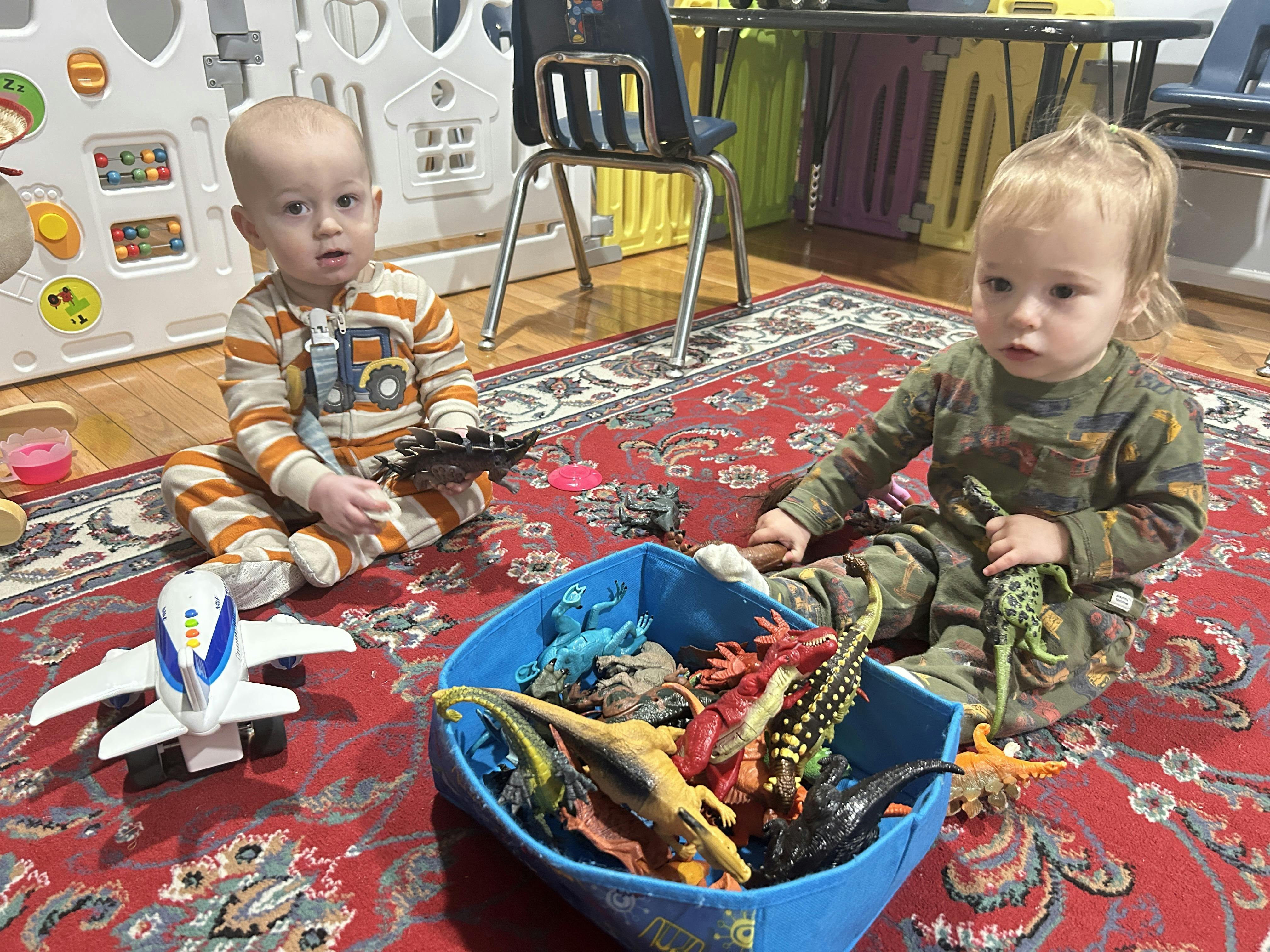 Two children playing with toys on a rug