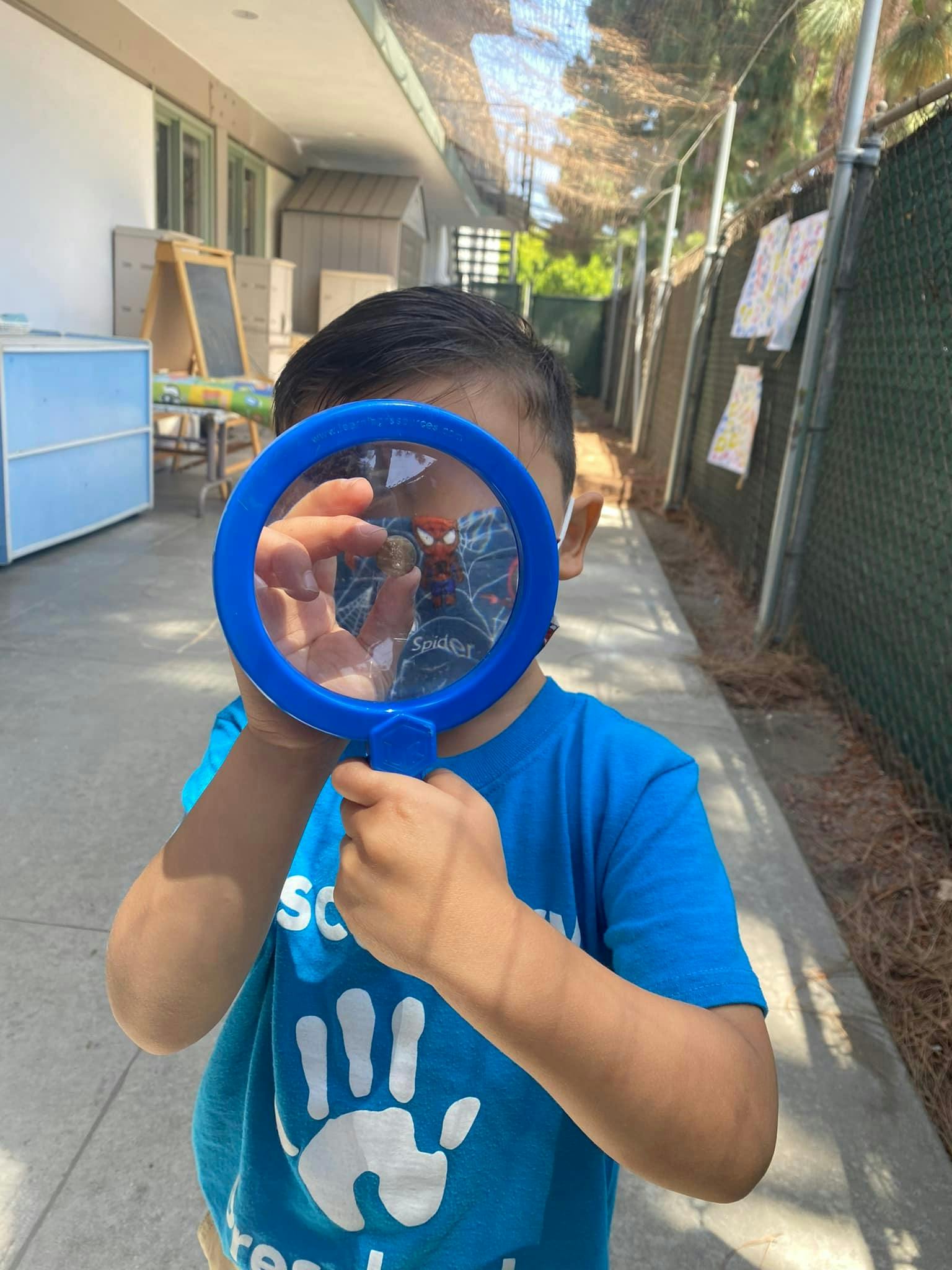 Child holding a blue magnifying glass in front of their face