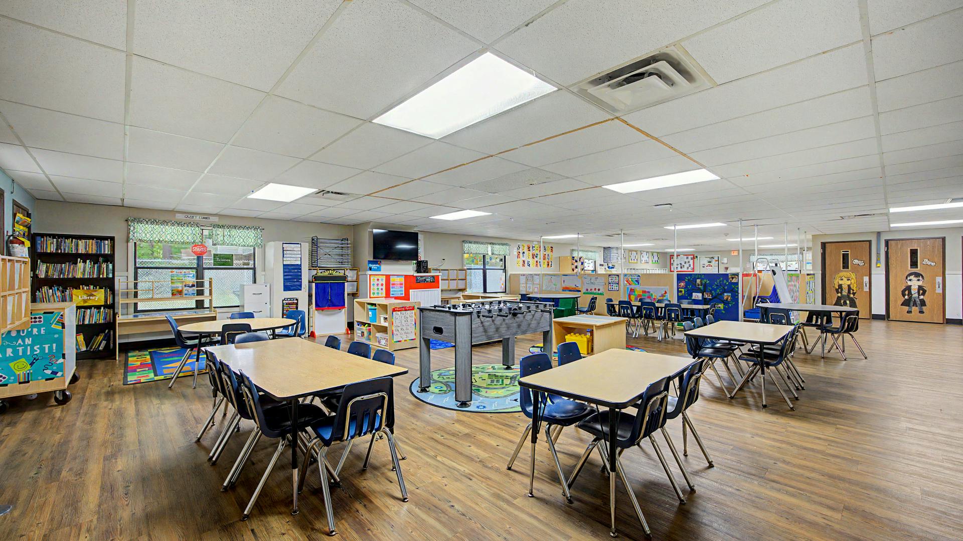 An empty early childhood classroom with small tables and chairs