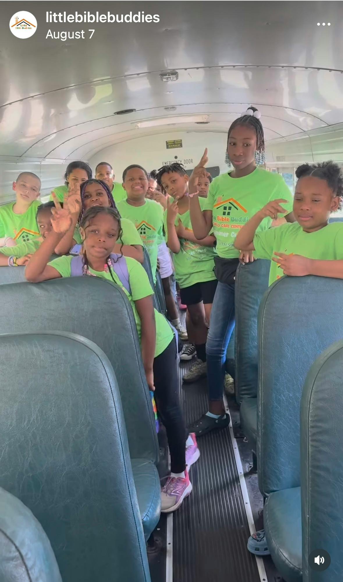 Group of children and teens in green shirts posing on a bus