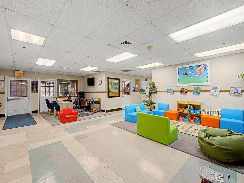 Children's room with colorful sofas, a beanbag, and books on a wall