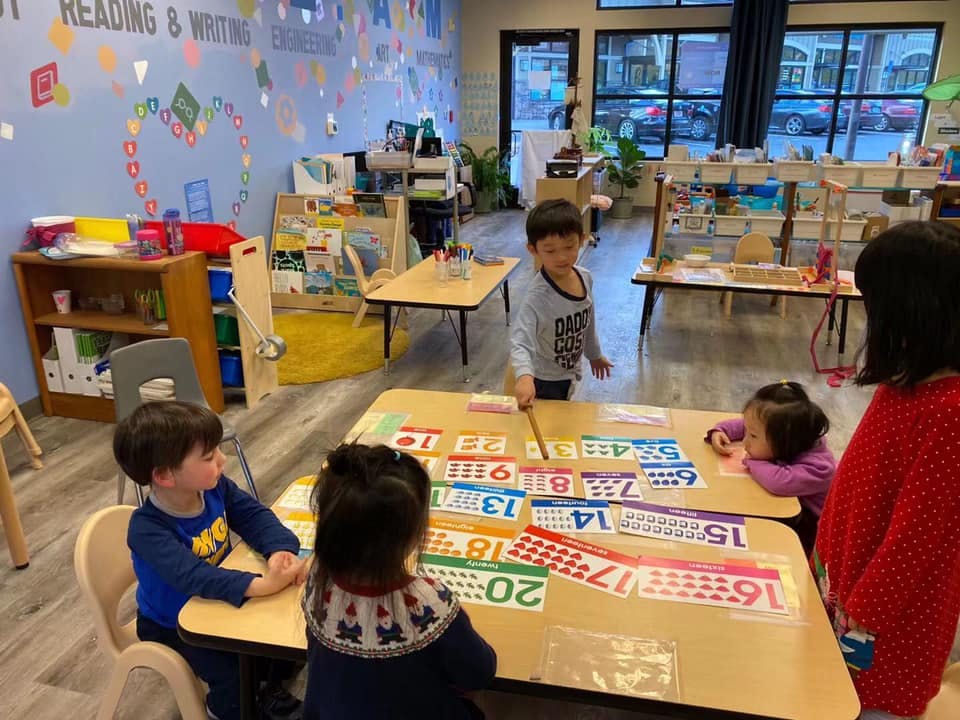 Children learning numbers at a table in a classroom
