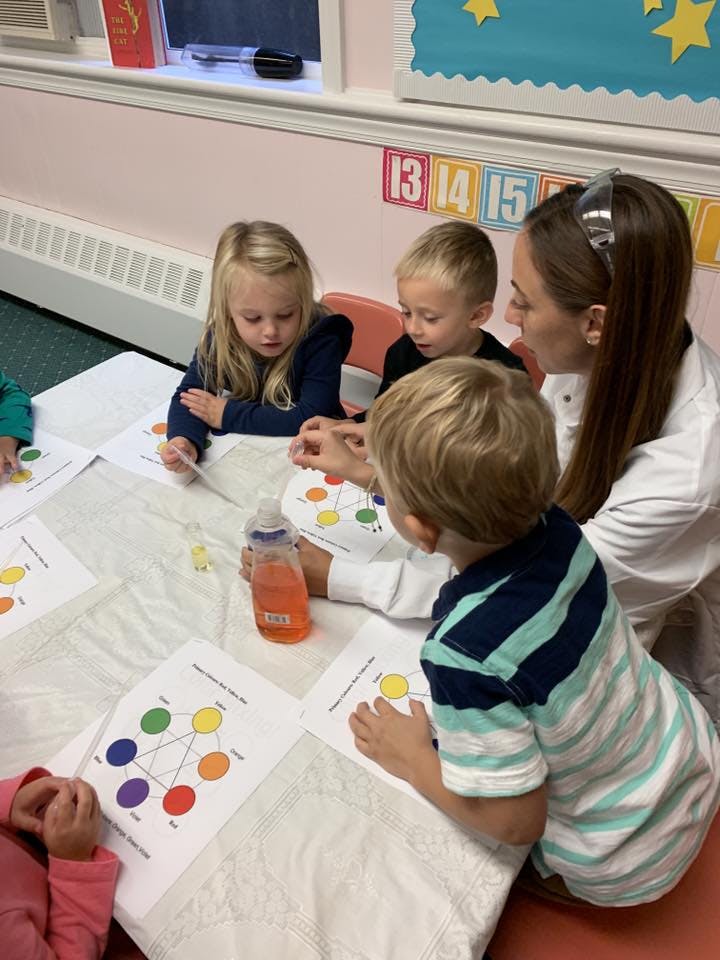 Adult and three children at a table with color wheel diagrams