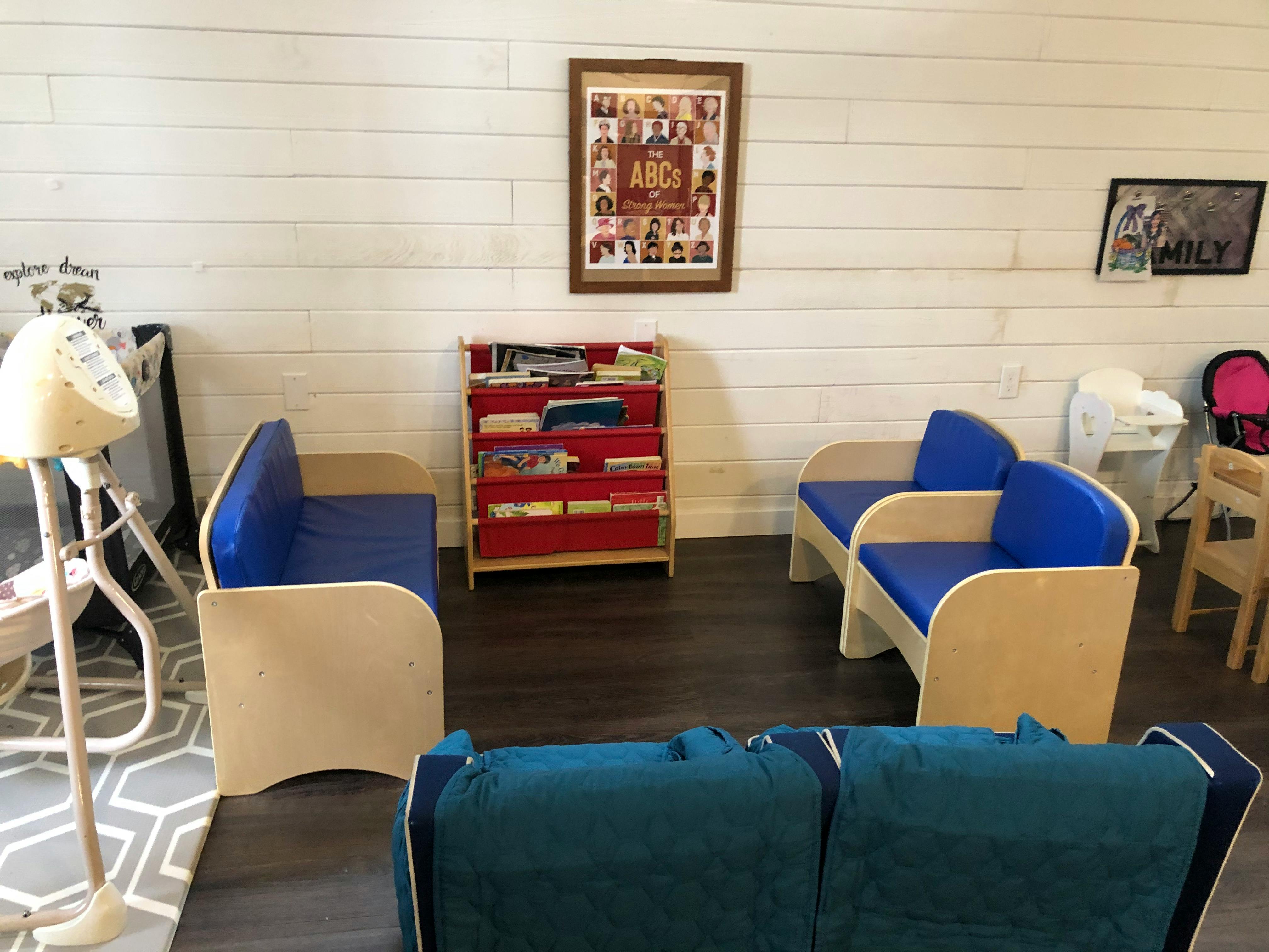 Children's seating area with blue chairs and a red bookshelf