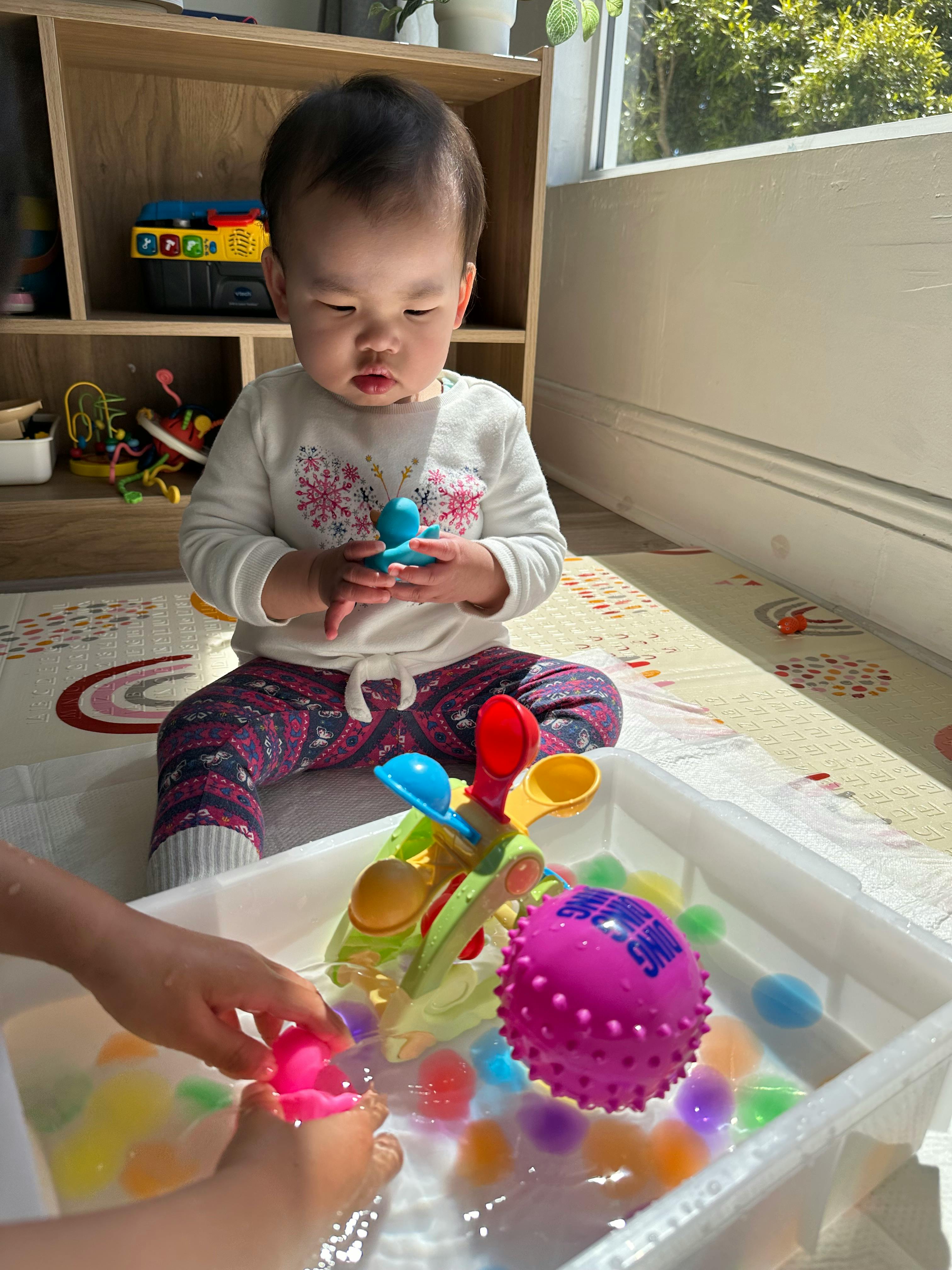 Child playing with water beads and toys in a bin