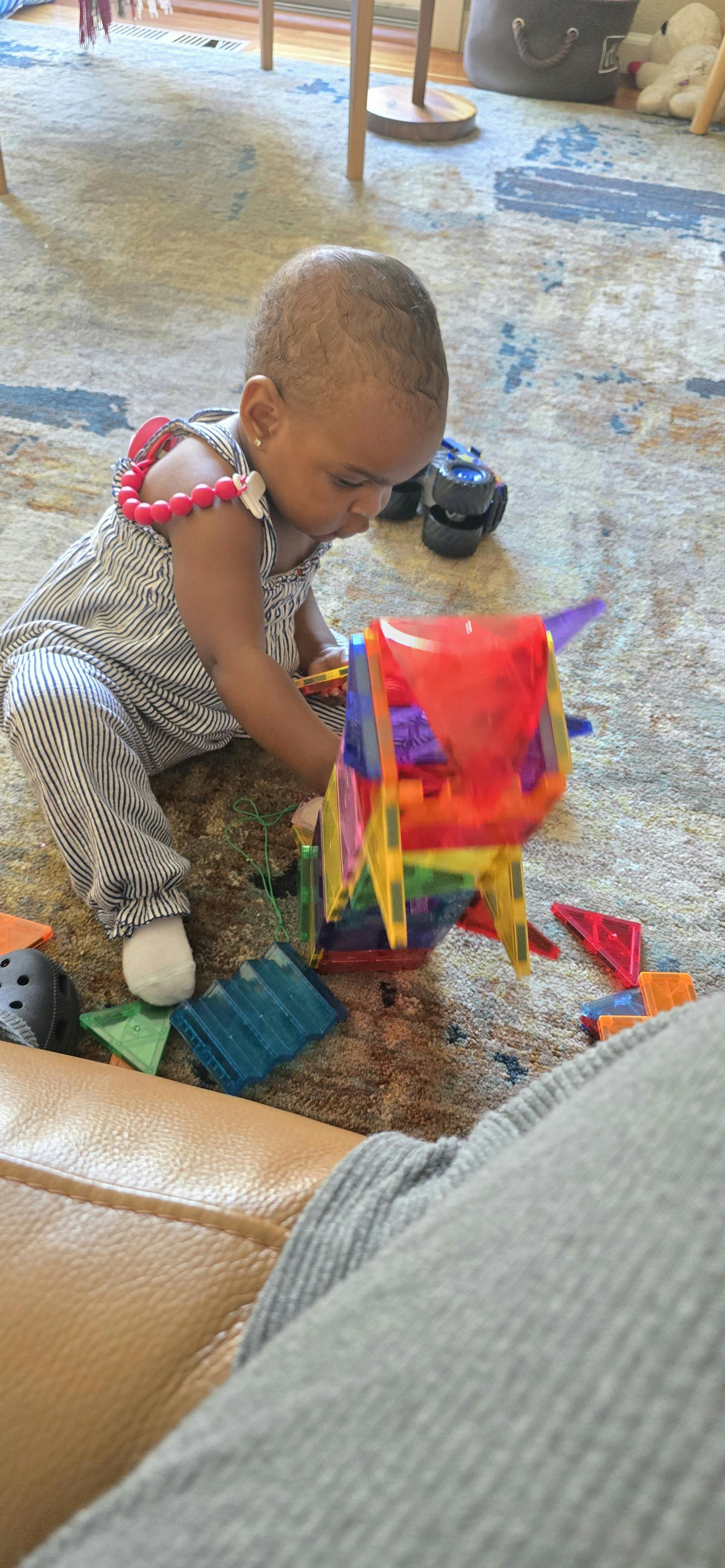 Child sitting on a rug and playing with magnetic building tiles