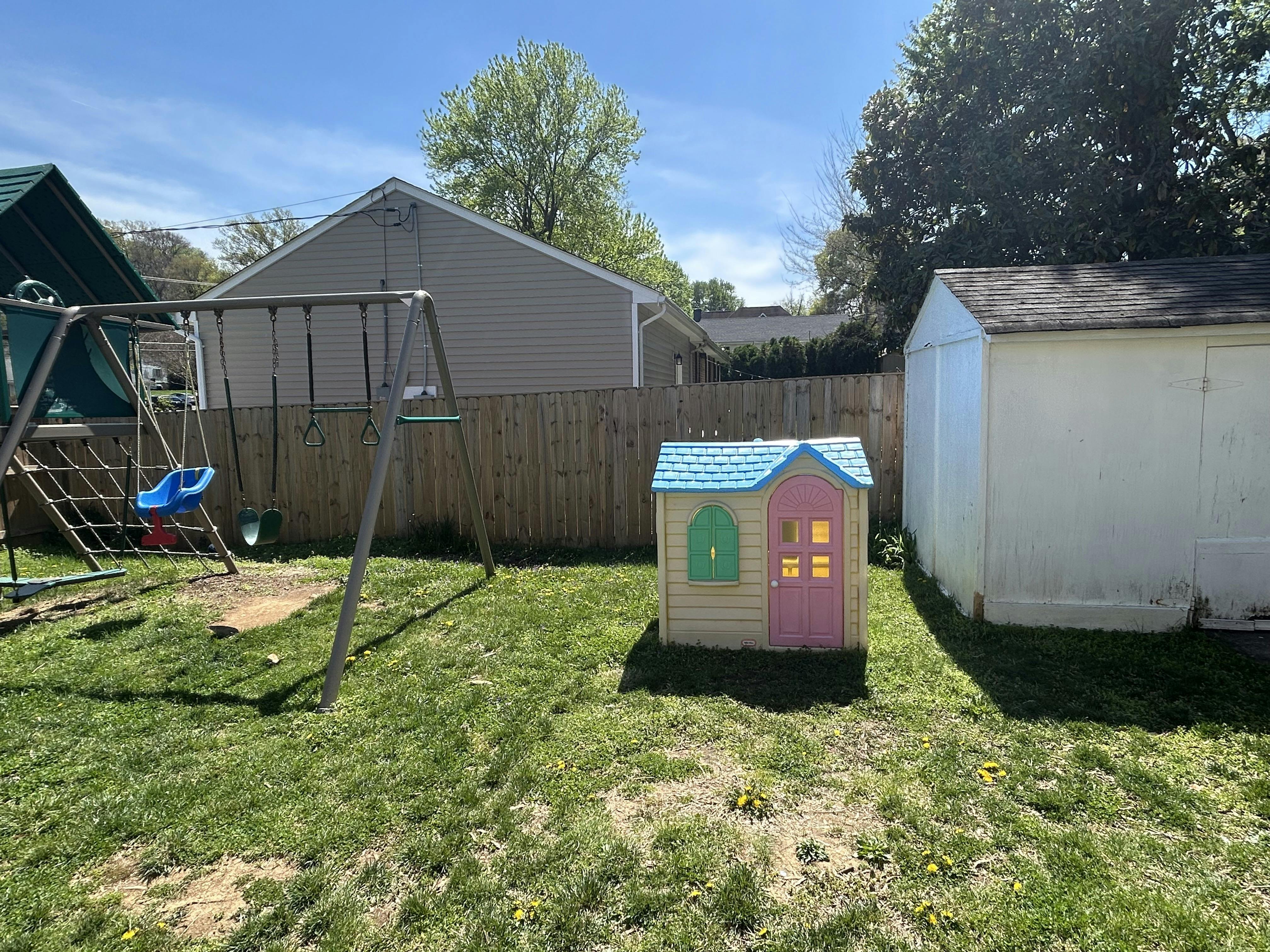 Playground with swings, small playhouse, and shed