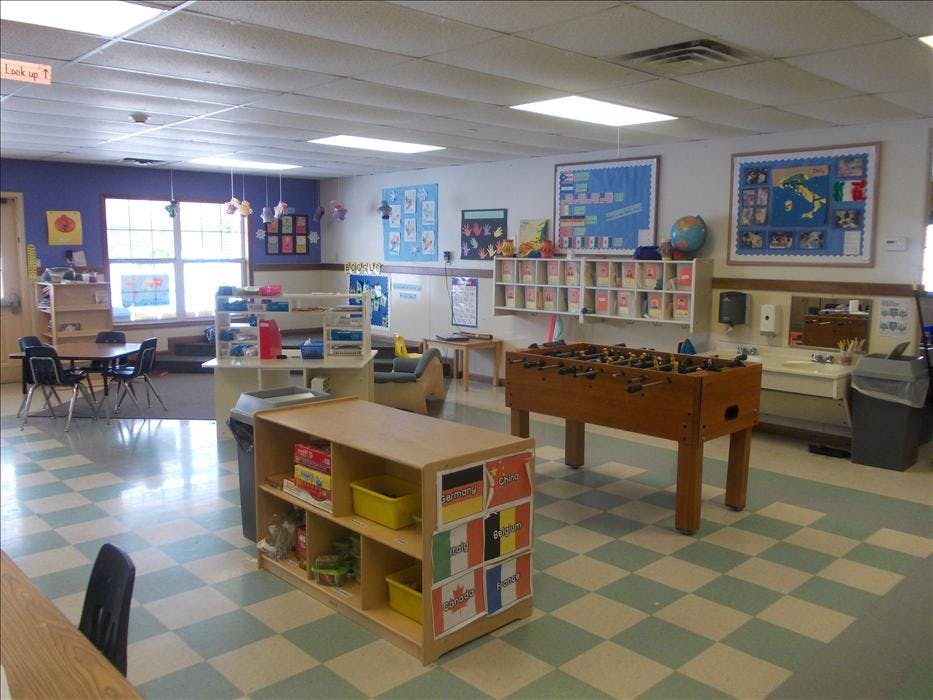 Classroom with tables, chairs, shelving units, and a foosball table