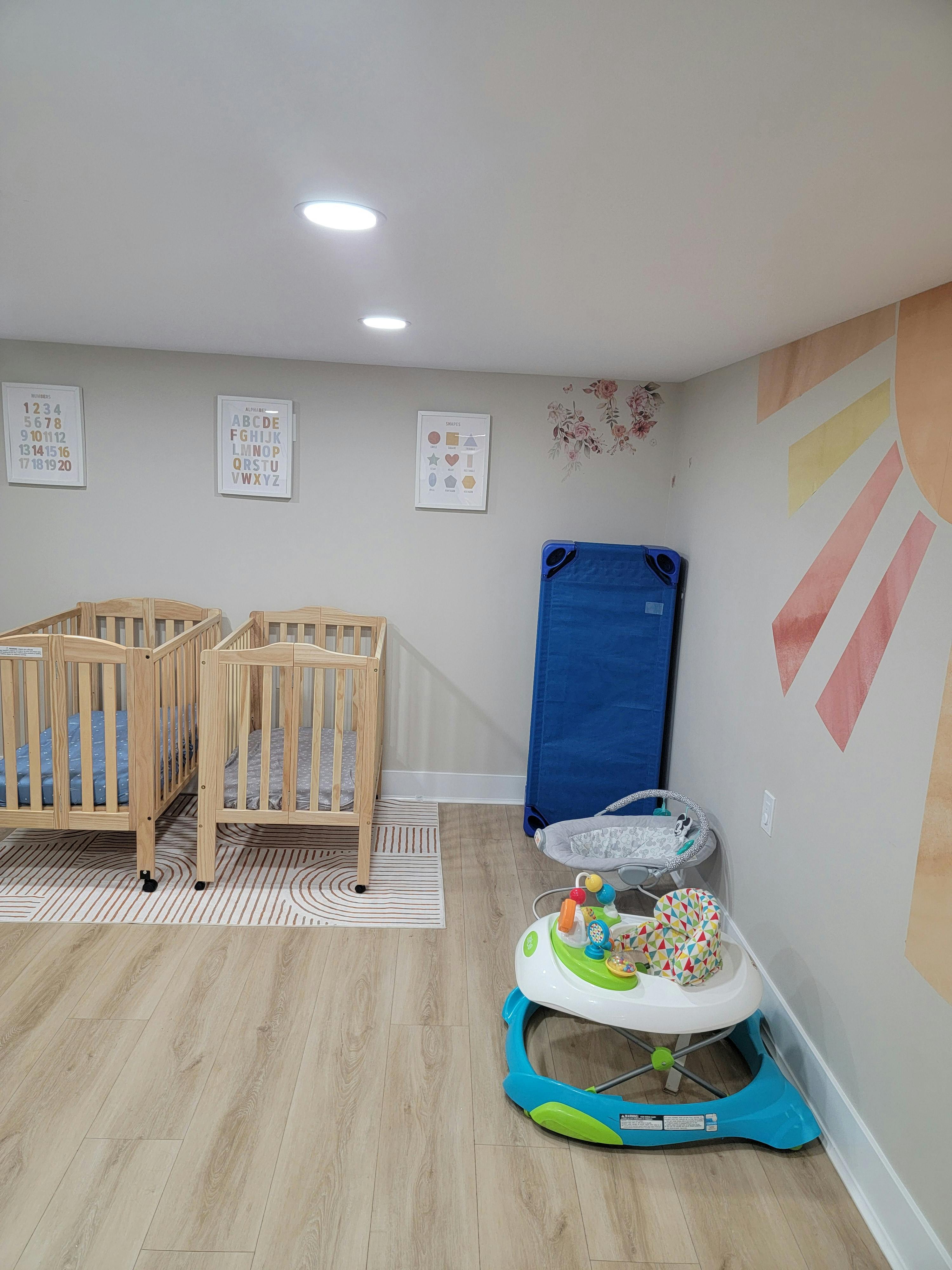 Two cribs and a baby walker in a room