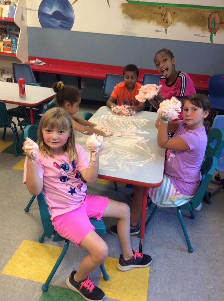 Children playing with shaving cream at a table