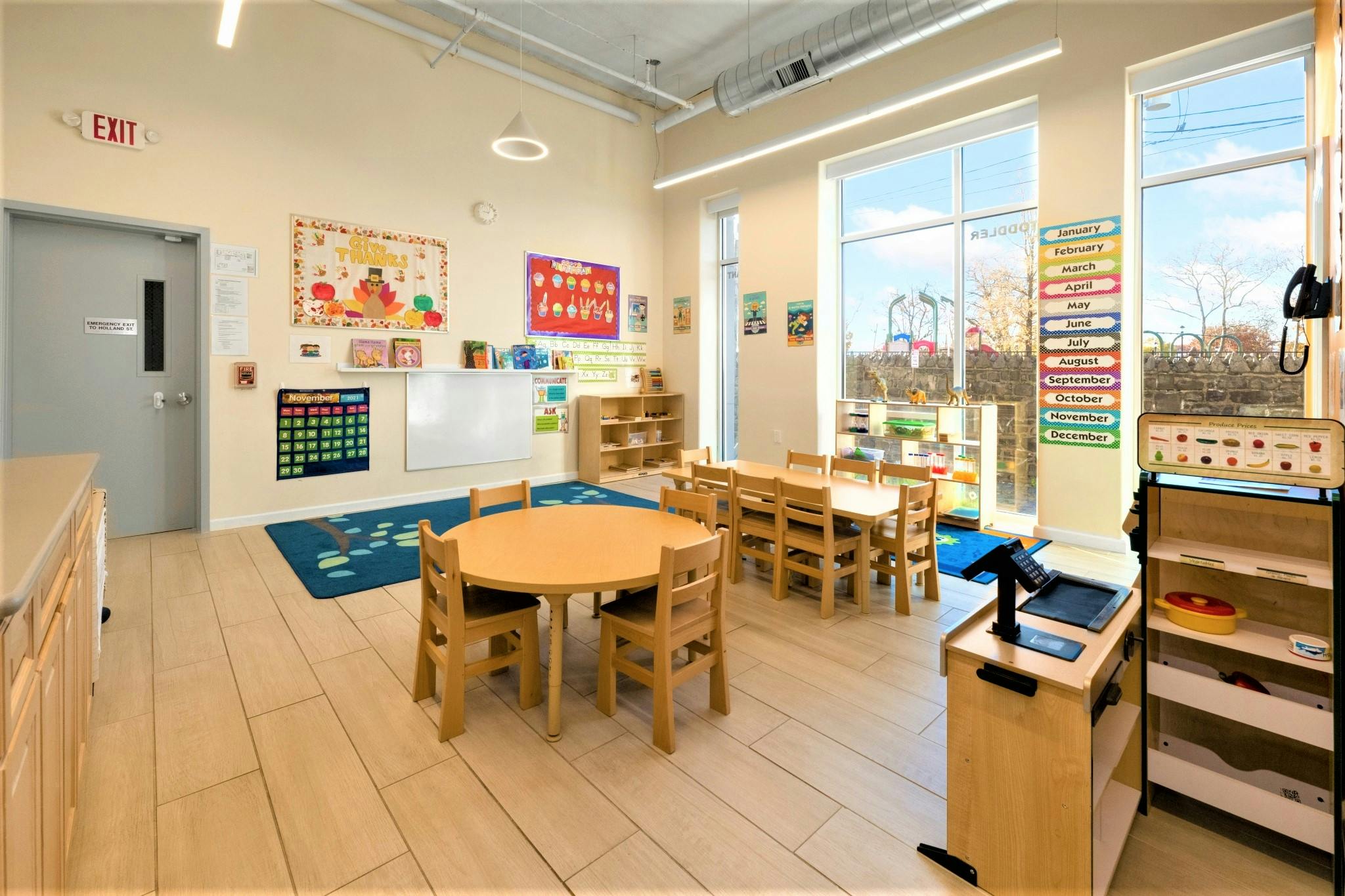 Empty classroom with small tables and chairs, large windows