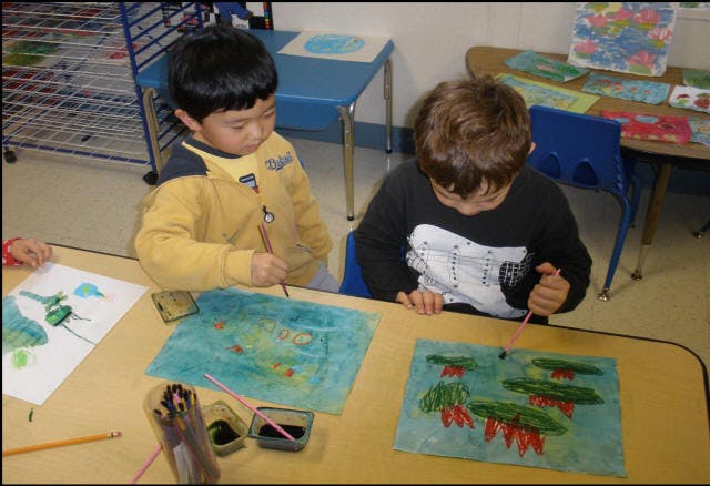 Two children painting at a table in a classroom