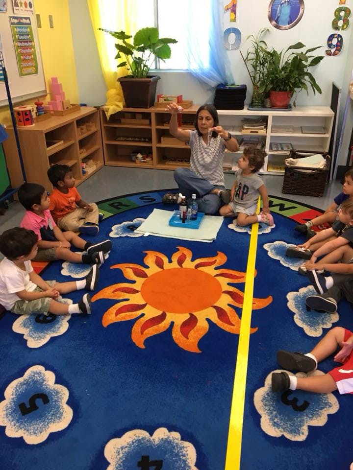 Adult and children sitting on a rug in a classroom