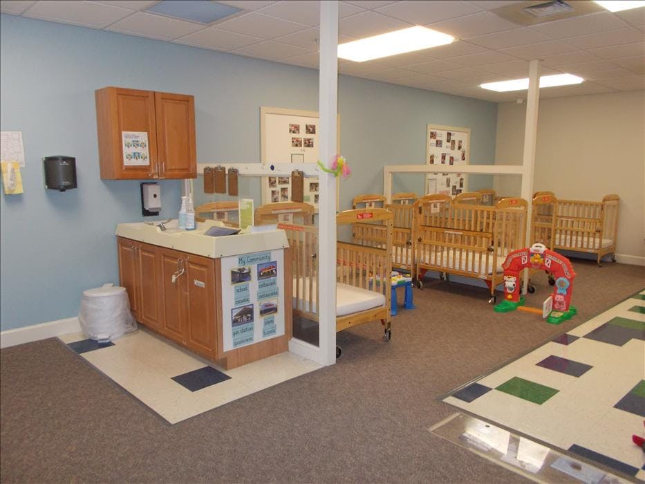 Multiple cribs in a room with a changing station and light blue walls