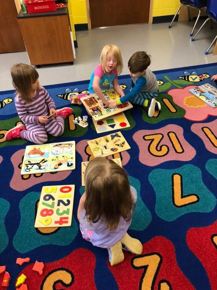 Children playing with puzzles on a colorful alphabet rug
