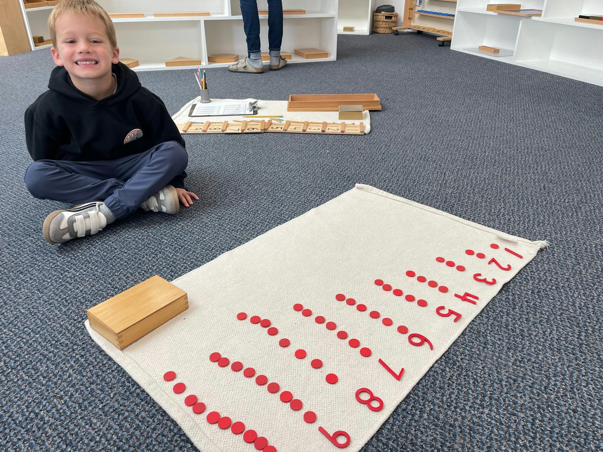 Child sitting on the floor with a counting activity on a rug