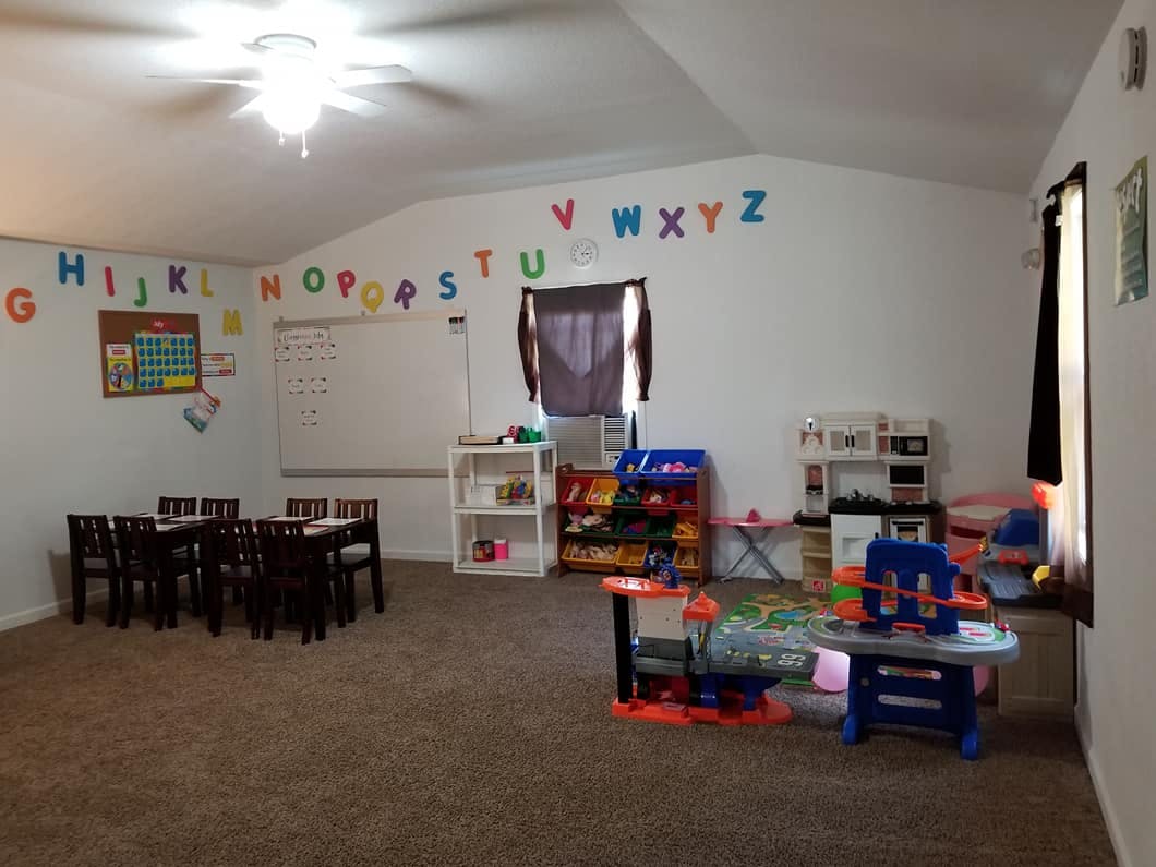 Playroom with alphabet letters on the wall, small tables and chairs, and toys
