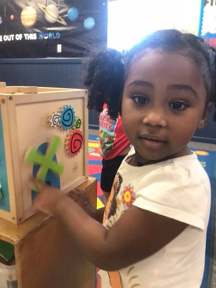 Child playing with a wooden activity cube