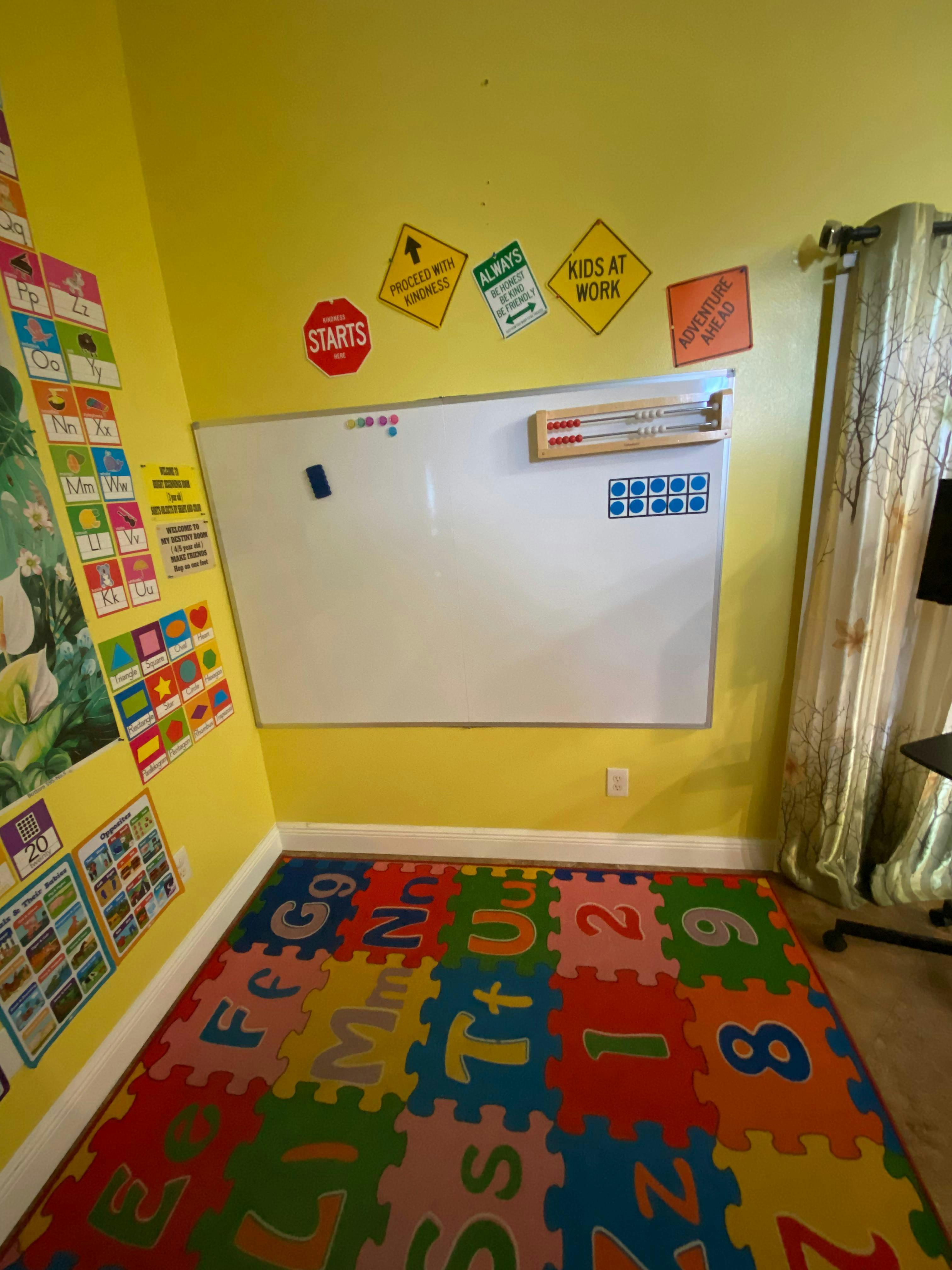 Classroom with a white board, letter and shape charts, and colorful alphabet floor mats