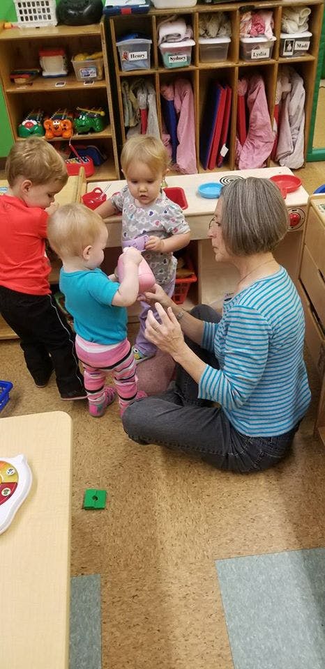 Adult and three children playing with toys in a classroom